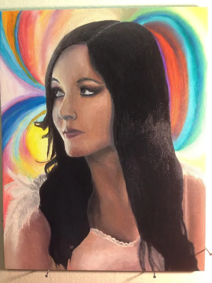 Portrait of a woman with long black hair and a white top against a rainbow background